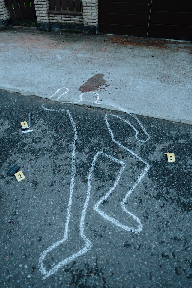 chalked outline of body at forensics scene on gravel floor
